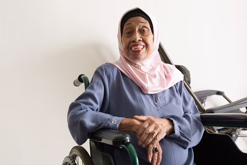 Portrait of elderly woman in traditional malay dress, smiling happily in a hdb rental flat. Photographed by Kelvin Lim in Singapore for Portraits of Love, HNF